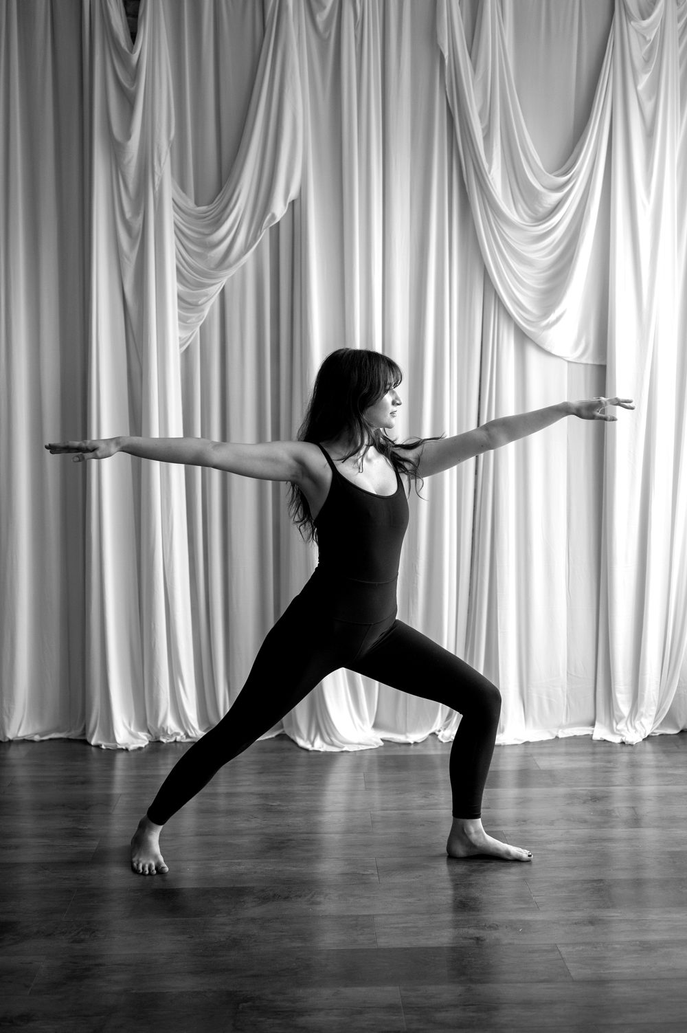 Instructor holding Warrior II pose, in black and white